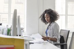 Side view of businesswoman holding letter and sitting at desk
