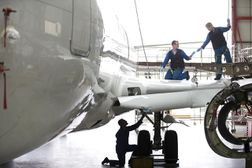Engineers repairing wing and landing gear on passenger jet in hangar