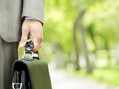 Lawyer walking in park setting holding a briefcase.