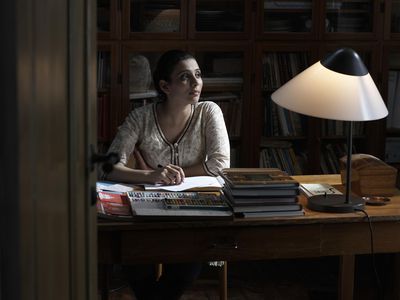 Woman drafting in long hand a first-person manuscript at her desk