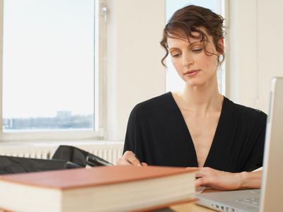 a woman working at a desk in front of an open laptop