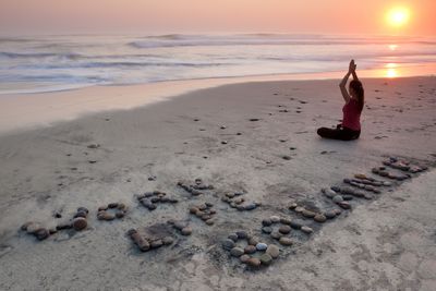 A woman practicing yoga on the beach as part of work-life balance