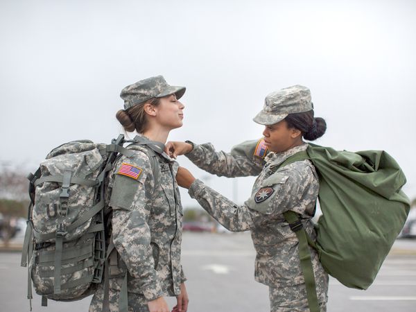 Female Soldier Helping Another Soldier with Shirt