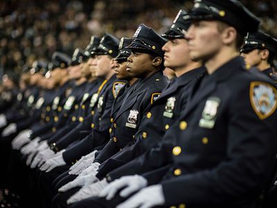 警察新兵在警察学院的仪式期间坐在关注。