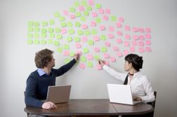 Two People Arranging Sticky Notes On Wall