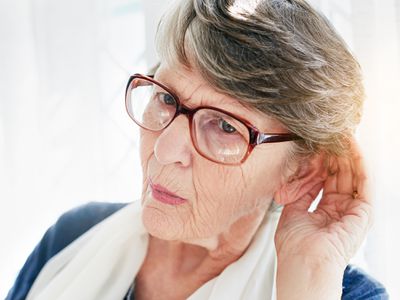 older woman with hand cupped to ear listening