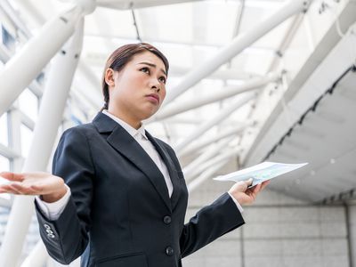 Professionally dressed woman shrugging in confusion after an involuntary demotion.