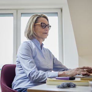 Mature woman at home using laptop at desk