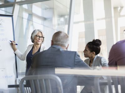 Businesswoman at whiteboard leading a meeting in conference room