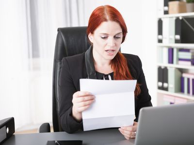 一位失业妇女在家里的办公室里读眼镜蛇的信。