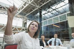 Businesswoman with dry erase marker creating a project budget in conference room