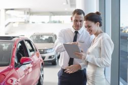 Salespeople in car dealership reviewing the weekly sales advertisement on a tablet device.