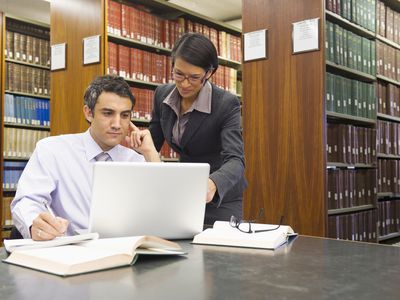 Two lawyers in a library in front of a laptop