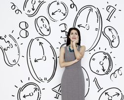 woman standing in front of illustrated wall with representations of time like clocks and numbers
