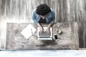 Overhead view of a woman using a computer whilst working/ studying in a modern looking room.