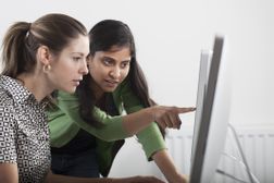 Manager teaching employee about computer programming