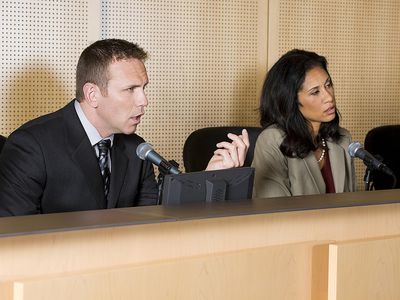 Two people on a dais, one talking into a microphone