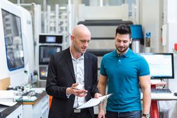 Businessman and employee discussing in modern factory