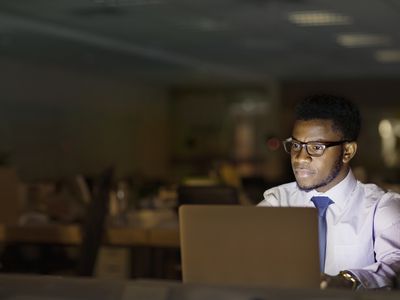 An attorney reading legal websites on a laptop at night in an office