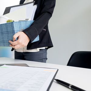 Woman holding box leaving office on last day on the job as she leaves for a career change.