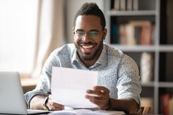 Man at a desk smiles while reading a letter.