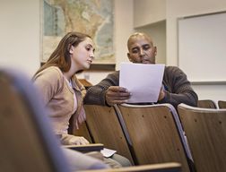 Professor and student reviewing essay in lecture hall