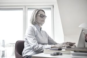 Mature woman at home using laptop at desk