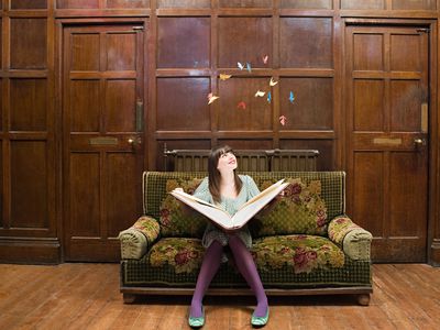 A teenage girl reading a large book