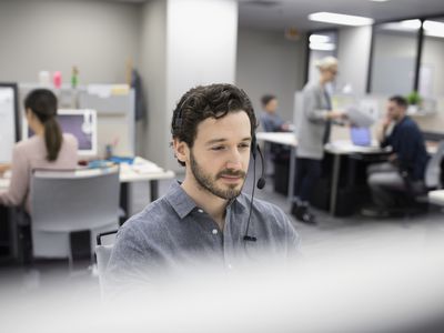Salesman talking on telephone with headset at cubicle