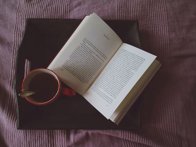 Directly Above Shot Of Open Book By Black Coffee In Cup On Tray At Bed