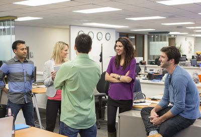 group of employees in an office building standing in a circle chatting