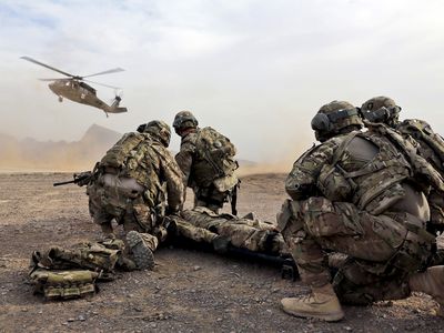Soldiers surrounding wounded comrade waiting for rescue helicopter
