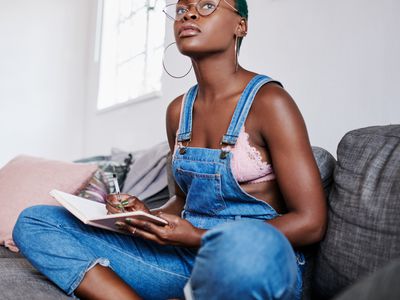 Woman writing in a notebook, looking off into the distance