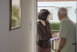 Researcher talking to elderly man on the doorstep