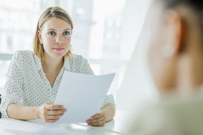 女人在面试中审查简历。“width=