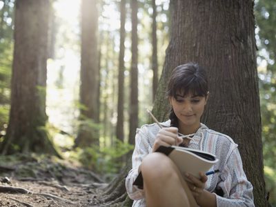 Woman writing dynamic characters with back to tree