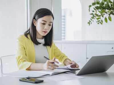 Woman sitting at desk with laptop writing