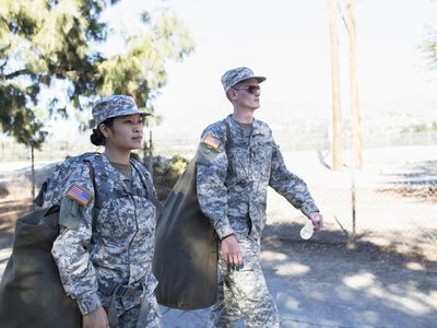 Army woman and man walking with duffelss