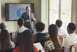 Businessman leading sales training at television screen