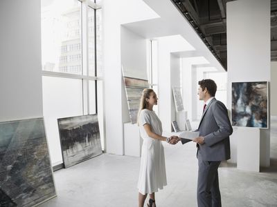 Art dealer and businessman shaking hands in an art gallery