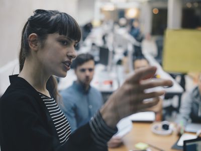 Computer programmer explaining adhesive note to colleagues in office