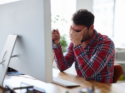 a young man sitting in front of computer looking exasperated