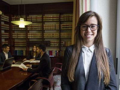 Portrait of female lawyer standing in boardroom with colleagues in background