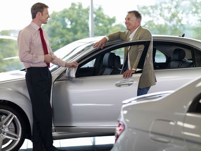Car Salesman talking to a customer in a dealer's showroom.