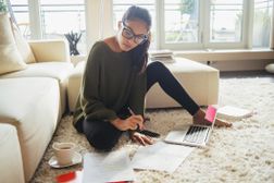 A young woman writes an abstract on a laptop surrounded by her notes and research. Learn how to write an abstract here.