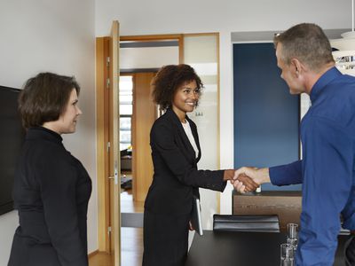 Hiring manager shaking hands with a prospective salesperson in an interview.