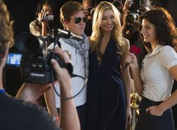 Journalist with microphone and celebrities at red carpet event