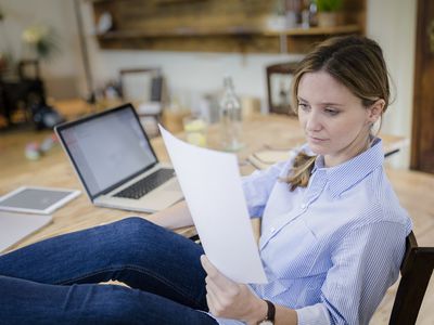 Woman sitting at desk at home with feet up reading a script