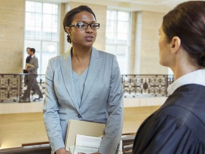 A law school graduate talking to a judge in a courthouse walkway hoping to get a job interview.