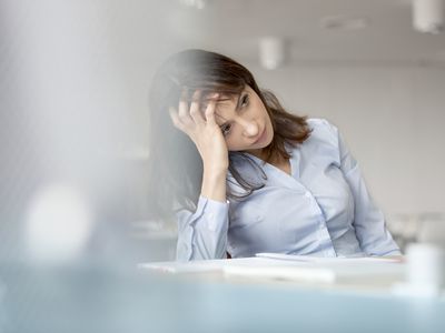 Tired businesswoman with head in hand looking away